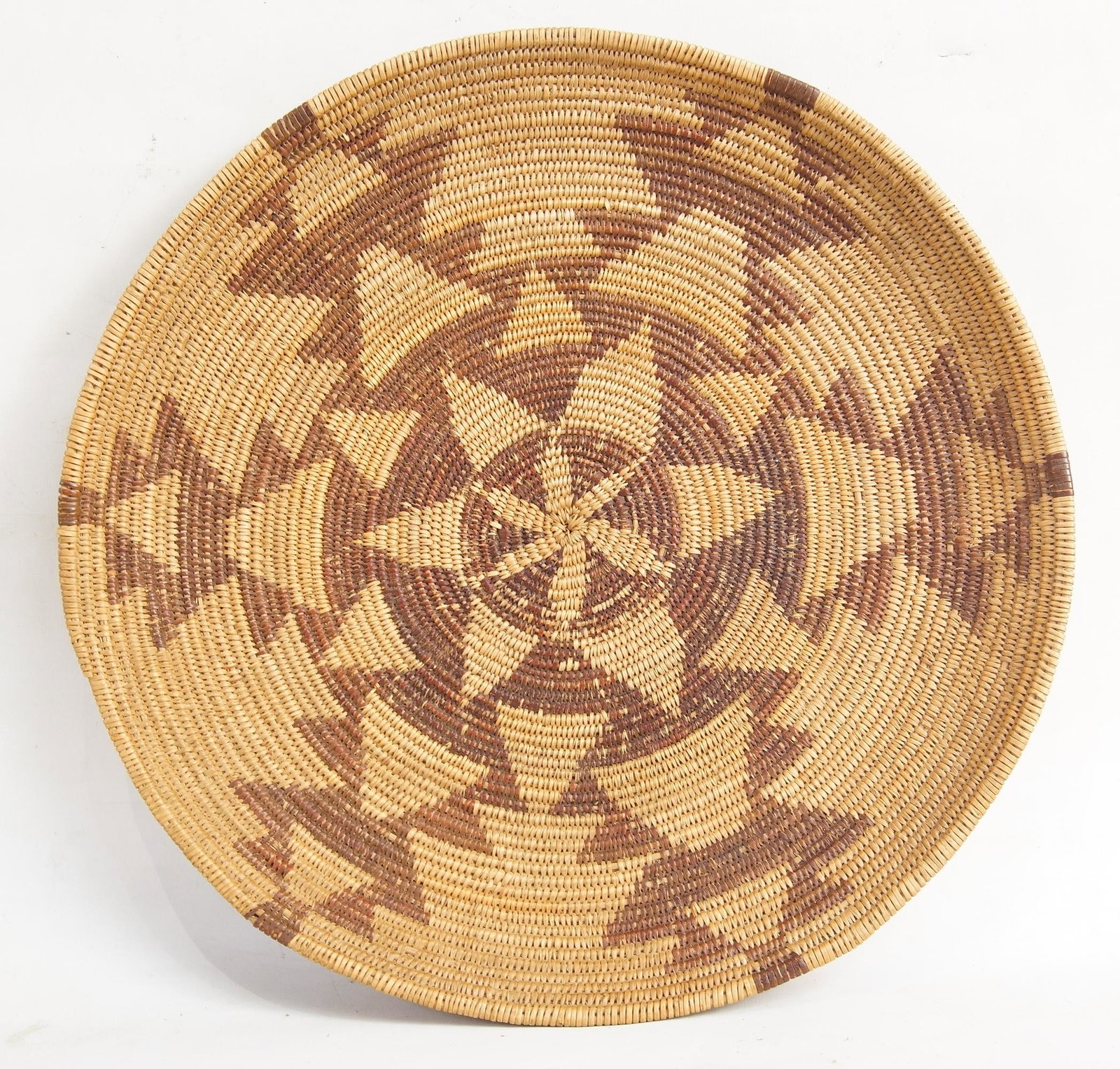 An Antique Apache Basket Tray: Apache Basket Tray circa 1920-1940's with concentric geometric triangle design with a central star in a polychrome brick red measures approx. 15.25" Provenance: Lifetime Native American Collection, Oj