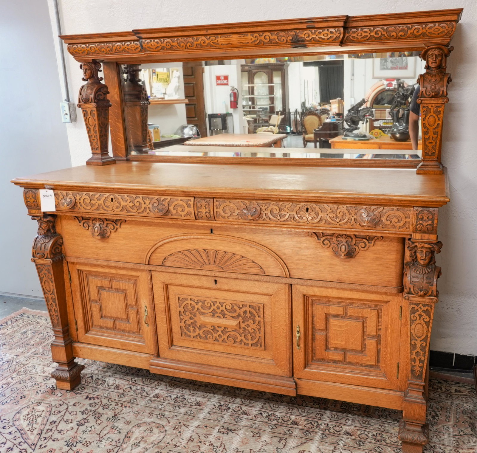 Antique American oak sideboard - Brown Derby: Highly carved quarter sawn American oak with beveled mirror and shelf that is carved with repeating arts & crafts like patterns, each column depicts a different bust both on top and at the front colum