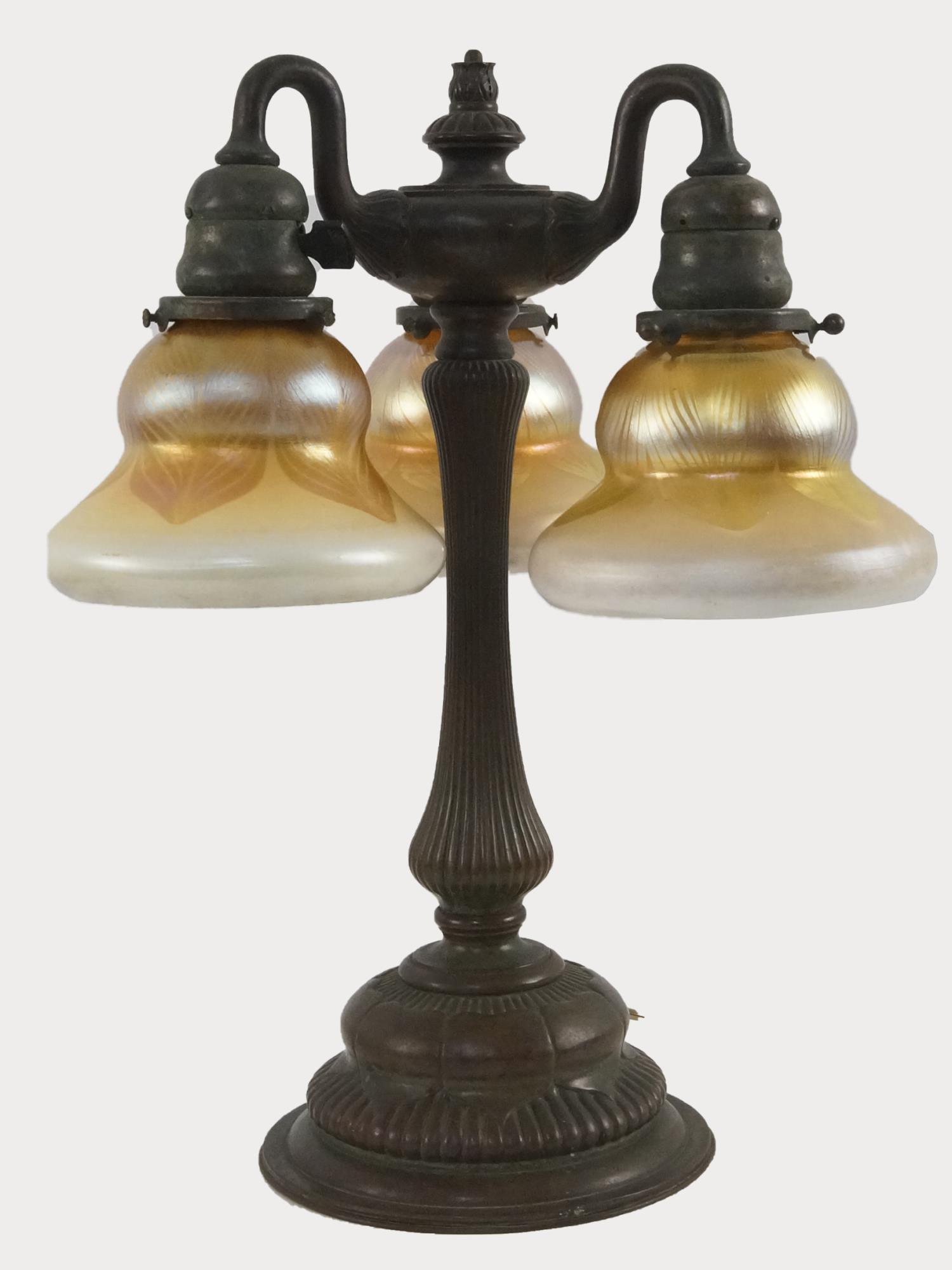 Tiffany Studios 309 Bronze Lamp Favrile Shades: TIFFANY STUDIOS NEWELL POST TABLE LAMP 309: Three lights. The base is signed Tiffany Studios New York 309, with original patina. Gold Favrile glass pulled feather shades are signed LCT. Please note on