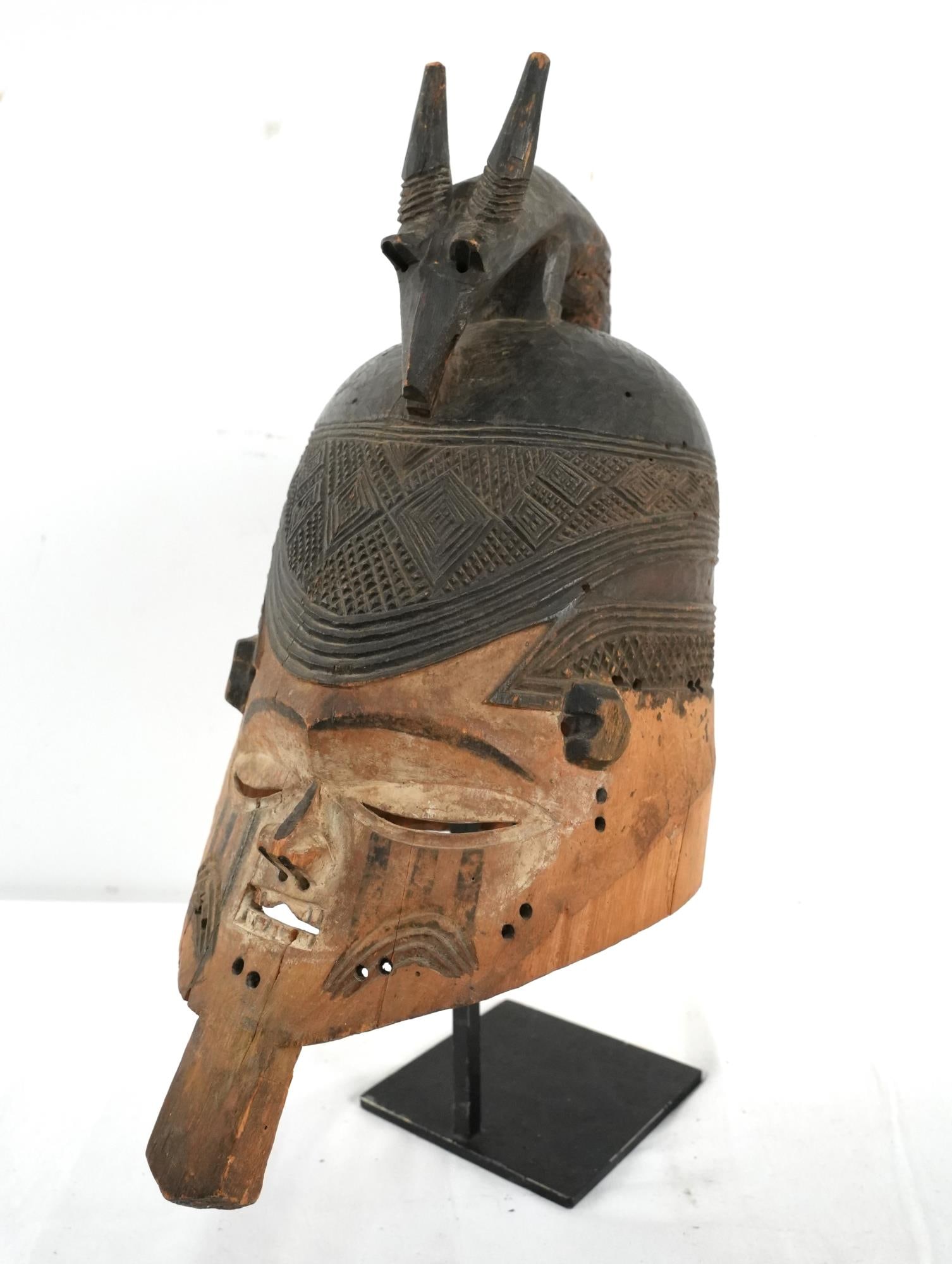 Suku D.R.C. helmet mask with Antelope: Antique Suku Helmet Mask shows age, blackened top with finely carved checking and diamonds, Antelope top (with some losses due to age), white and black painted face on natural wood with teeth measures