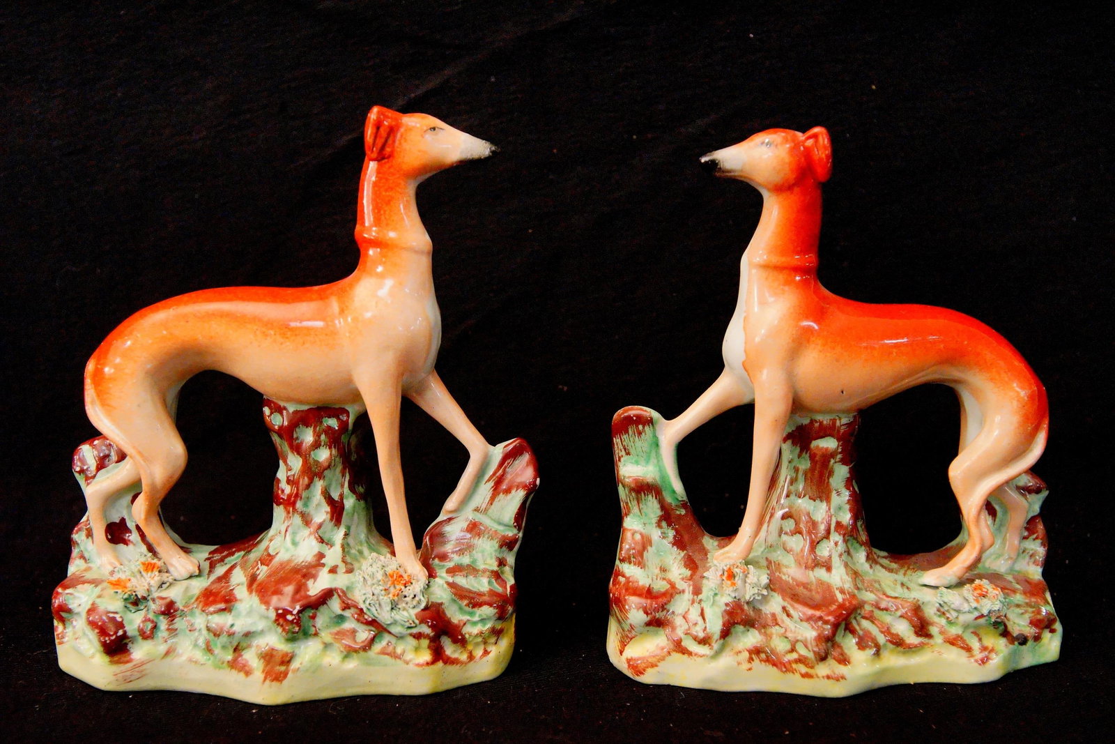 Pair of Antique English Staffordshire Whippets: 19th century both are standing on shaped and glazed green foliate base with a gradient red coat, - 6.5" x 6" Provenance: Montecito, Ca Estate collection and Allison Moore Guarantee decal