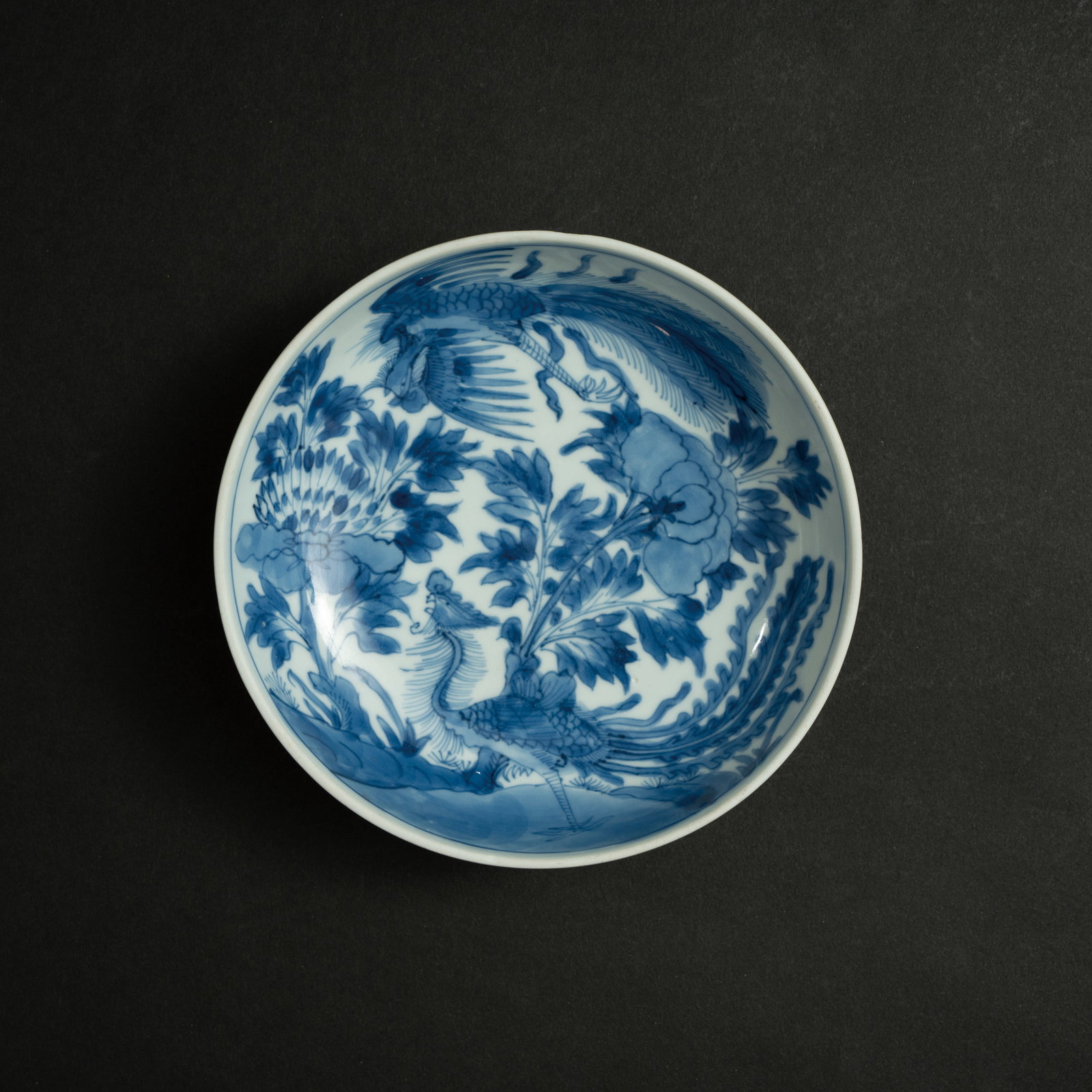 A BLUE AND WHITE 'PHOENIX AND PEONY' DISH QING DYNASTY, KANGXI PERIOD 清康熙: A BLUE AND WHITE 'PHOENIX AND PEONY' DISHQING DYNASTY, KANGXI PERIOD清康熙 青花凤穿牡丹纹盘ESTIMATE: $1,500 – $2,500DescriptionT
