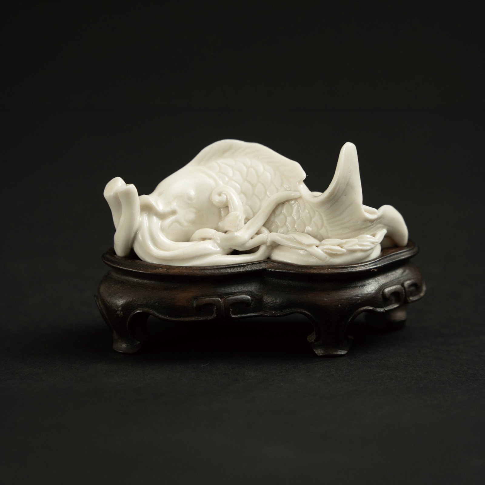 A DEHUA WHITE-GLAZED 'CARP' PAPERWEIGHT MING DYNASTY 明 德化窑白: A DEHUA WHITE-GLAZED 'CARP' PAPERWEIGHTMING DYNASTY明 德化窑白釉鱼形文镇ESTIMATE: $800 – $1,500DescriptionThis exquisitely modeled pap
