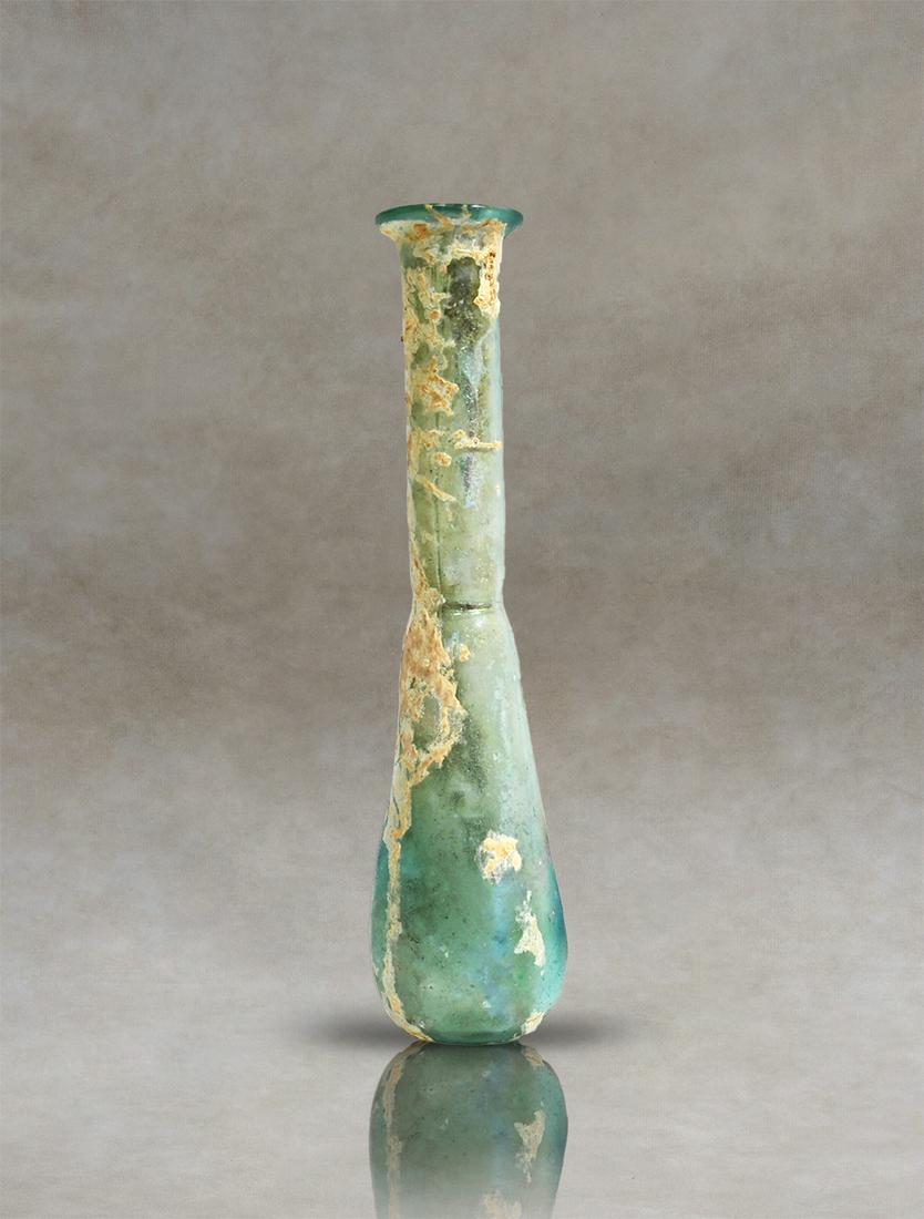 Roman Glass Unguentarium Perfume Bottle: An antique Roman translucent-glass unguentary. It has an elongated pyriform body with a small narrowing at the base of the cylindrical neck and an inwardly folded rim. The base is flattened.Inventory 