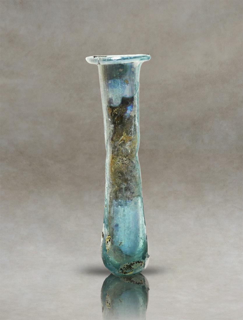 Patinated Roman Glass Transparent Unguentarium Perfume Bottle: Ancient Roman glass perfume holder. It has a pyriform body, with a small narrowing at the base of the cylindrical neck and an outward-folding rim. Inventory code : SG40