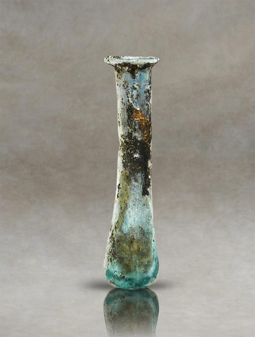 Roman Glass Unguentarium Perfume Bottle: An antique Roman translucent-blue-glass unguentary. It has an elongated pyriform body with a small narrowing at the base of the cylindrical neck and an inwardly folded rim. The base is flattened.Inven