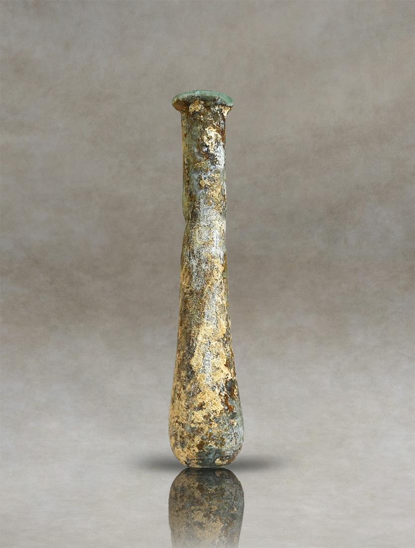 Roman transparent Glass Unguentarium: Roman pale-green blown glass, probably used as a perfume bottle. The vessel has a flattened rim and a long, narrow cylindrical neck that widens towards the body. The lower part of the curve curves inw