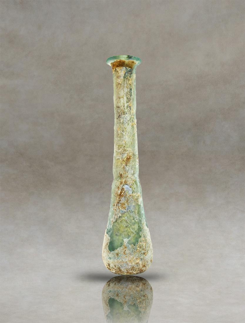 Roman Glass Unguentarium Perfume Bottle: An antique Roman translucent-glass unguentary. It has an elongated pyriform body with a small narrowing at the base of the cylindrical neck and an inwardly folded rim. The base is flattened.Inventory 