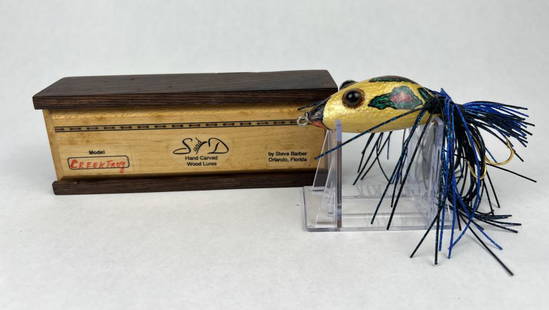 S & D "Creek Frog" fishing lure: Florida made lure by Steve Barber, hand carved and painted wood, signed under, with custom box. Condition: Presenting nicely, box is a little tight to close. Dimensions: Box: L 6" Lure: L 3.5â