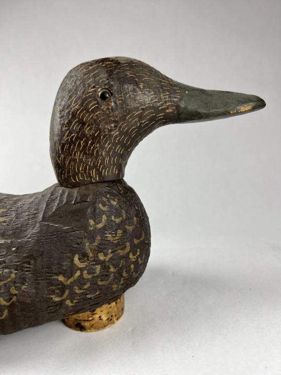 Duck Decoy: Antique painted wood duck decoy, unsigned. Hollowed out bottom, cork float. Condition: Some gauges, minor separation at neck, scuffs and scratches. Dimensions: H 7" x L 17" x W 5.5"