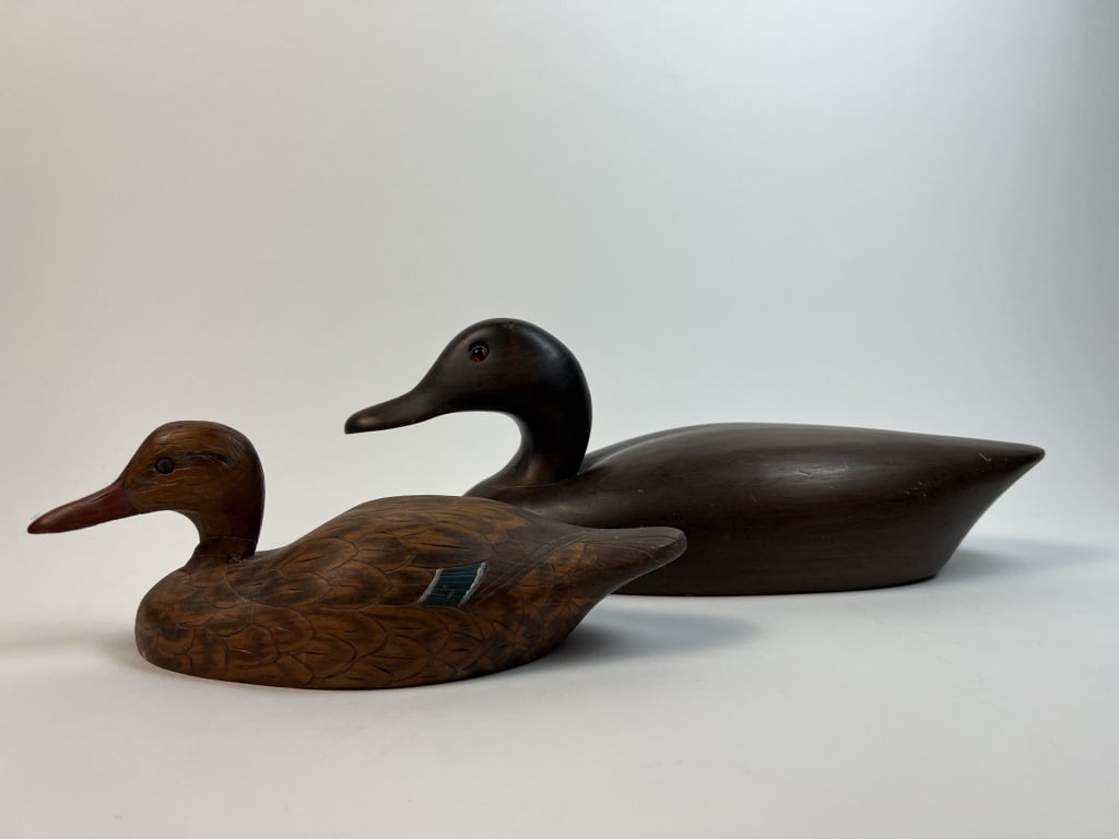 (2) duck decoys: Both signed under. Dimensions: L 14" x W 5.5" Condition: Both with nicks and scratches, smaller with repair to neck.