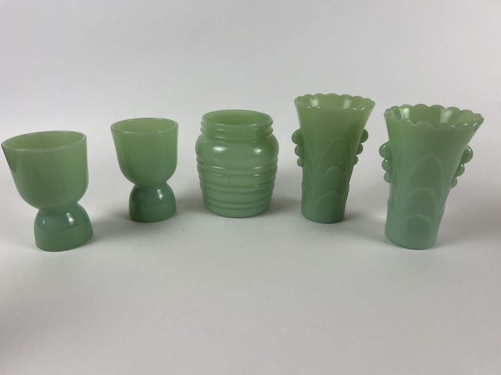 Fire-King style Jadeite grouping: A honey pot, two egg cups and a pair of vases, none marked. Dimensions: Vase: H 5.5" Condition: As shown, honey pot with interior chip.