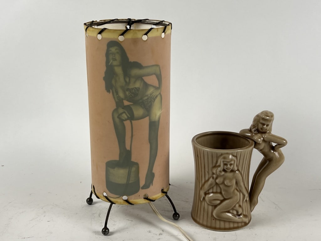 (2) Deco Pin up decorative objects: A made in Japan ceramic mug and a working lgiht by Red Light Distric Co, Orange Ca. Dimensions: H 10" x Dia: 4.25" Condition: Some crazing, age staining to lamp.