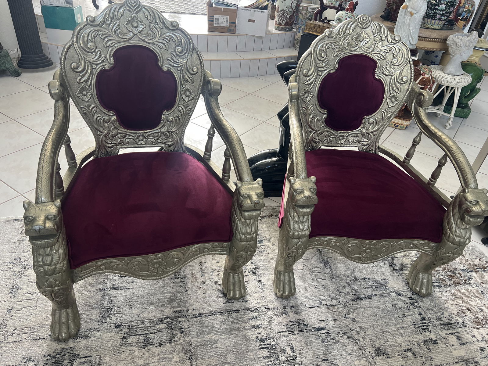 Lion Head Silver Clad Pair of Chairs: A pair of Victorian style throne chairs, lovely burgandy velvet, carved wood with lion head accents and silver overlay. Condition: One with nick to nose. L 30" x H 39" x D 24" Low Estimate: