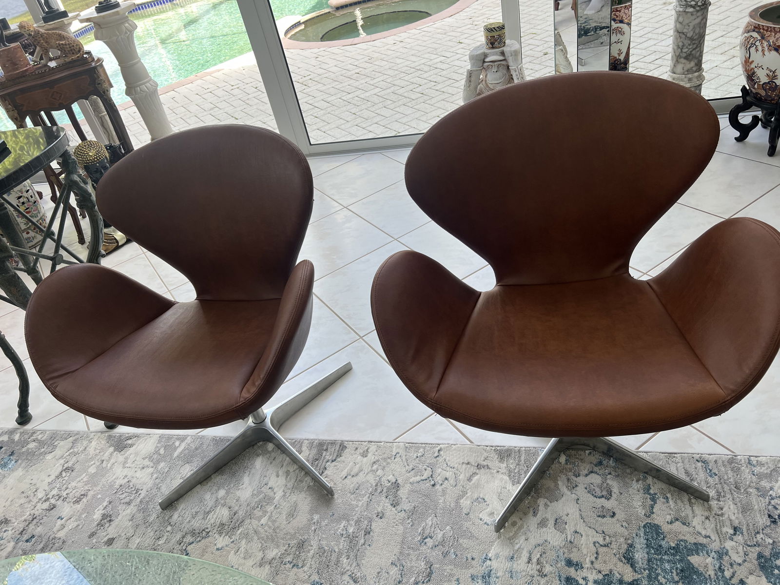 (2) Swan Style Chairs: A pair of chairs after Arne Jocobsen, taupe or saddle color quality leather, swiveling. Not vintage. Dimensions: W 28" x D 18" x H 33" x Seat Height:17.5" Condition: One small blemish to leather. Low