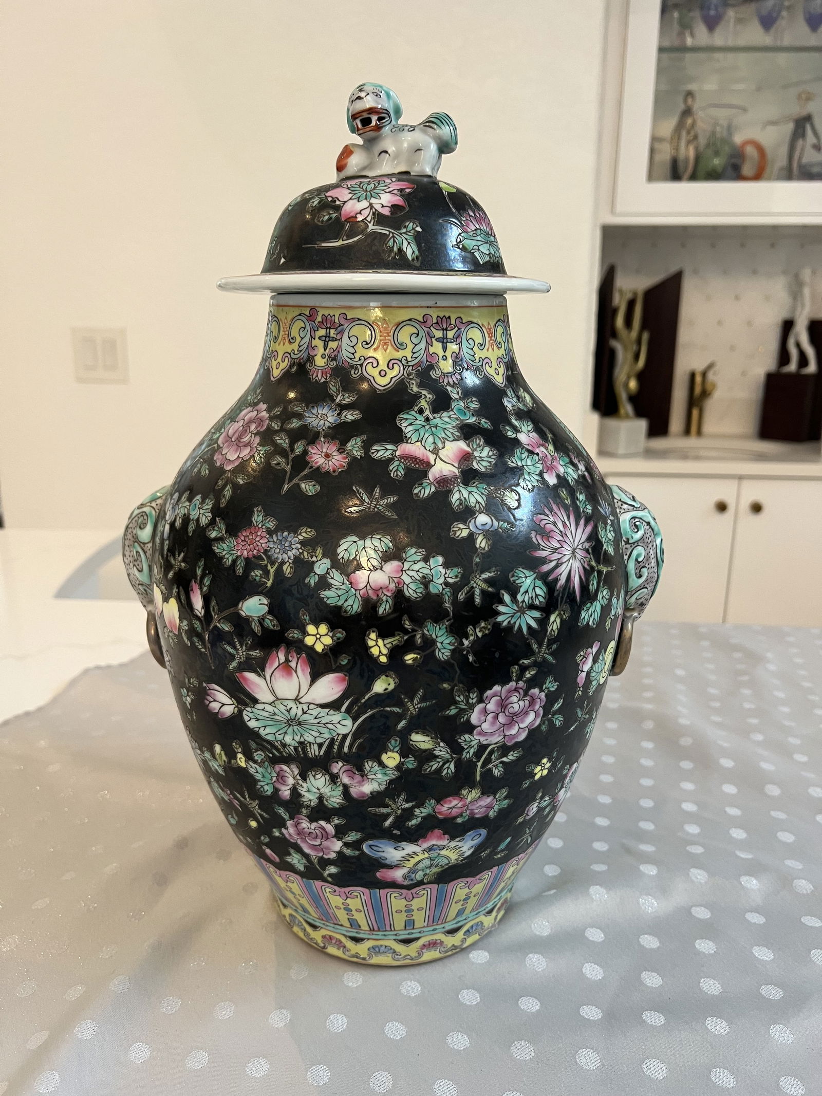 Famille Noire Porcelain Covered Ginger Jar: Floral and butterly decor, foo dog finial, elephant side. Chinoserie style. Dimensions: H 17" x W 11" Condition: Only minor signs of age. Low Estimate: 200.00High Estimate: 400.00