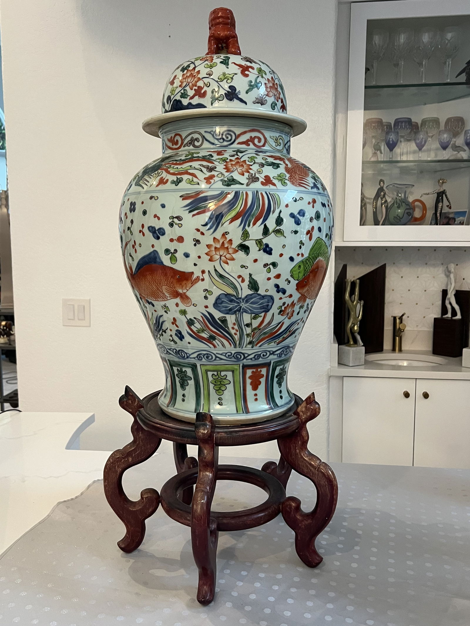 Signed Chinese Ginger Jar: Covered temple jar or ginger jar, foo dog top, on wooden base. With birds, koi fish, dragons and floral design. Dimensions: overall (including base) H 35" x Dia: 14" Condition: One repair to foo dog.