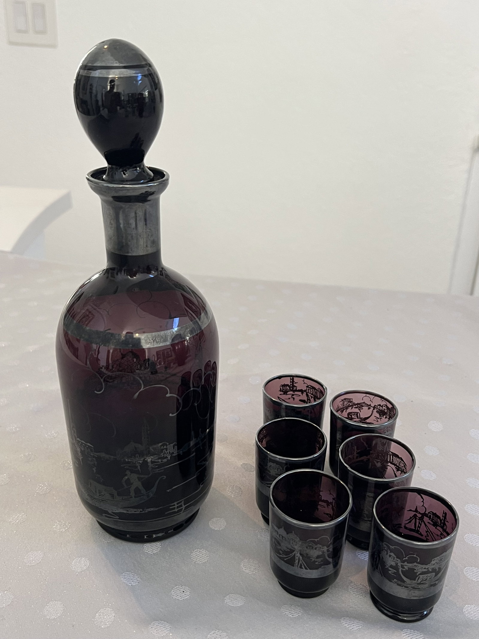 Amethyst Silver Overlay Glass Decanter: Italian, Venetian purple glass antique decanter and six glasses. Silver overlay. Dimensions: Decanter: H 10.5" x W 4" Condition: Minor wear to overlay. Low Estimate: 200.00High Estimate: 300.00