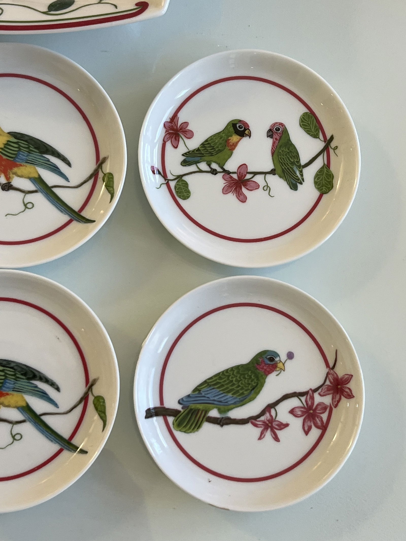 Lynn Chase Parrots of Paradise Bowl and Coaster Set: A grouping of 6 coasters and one candy dish. Porcelain with colorful parrots, 1989, Made in Japan. Dimensions: Bowl: H 1.5" x W 8" x D 6.5" Coaster: Dia: 4' (almost) Conditon: No issues to note. Low