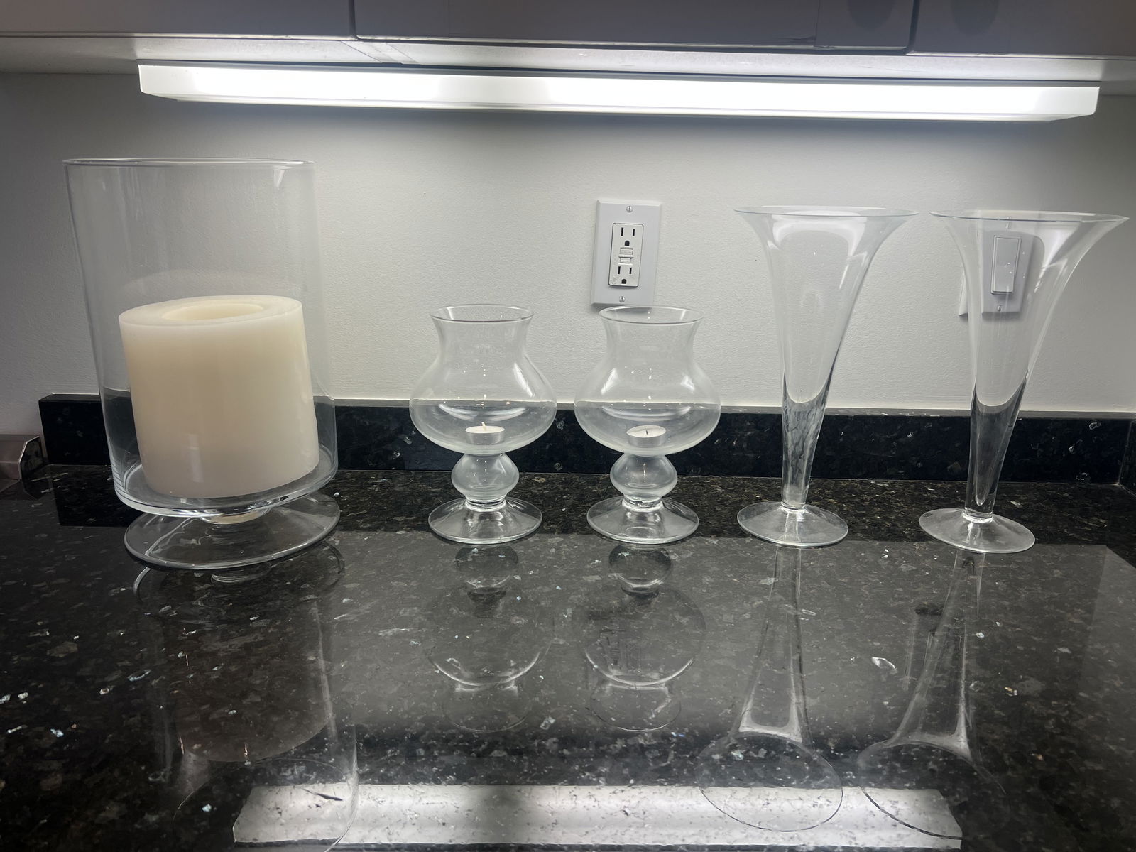 Grouping of Candle Hurricane Holders: A large Simon Pierce? hurricane measuring H13.5" x Dia: 7.5" with battery operated candle. The pair of trumpet vases are signed with an etched M under. (chips to edges of these) Low Estimate: