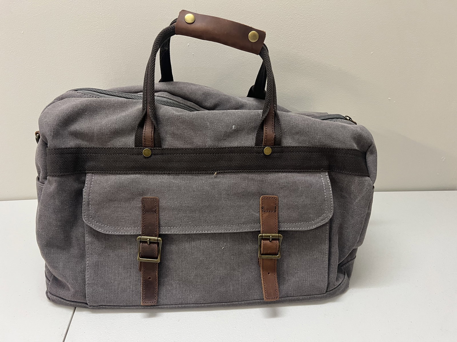 Canvas Overnight Carry On Duffel Bag: Gray canvas and brown leather. Dimensions: L 20" x W 12" Condition: Very lightly used. Low Estimate: 10.00 High Estimate: 10000.00