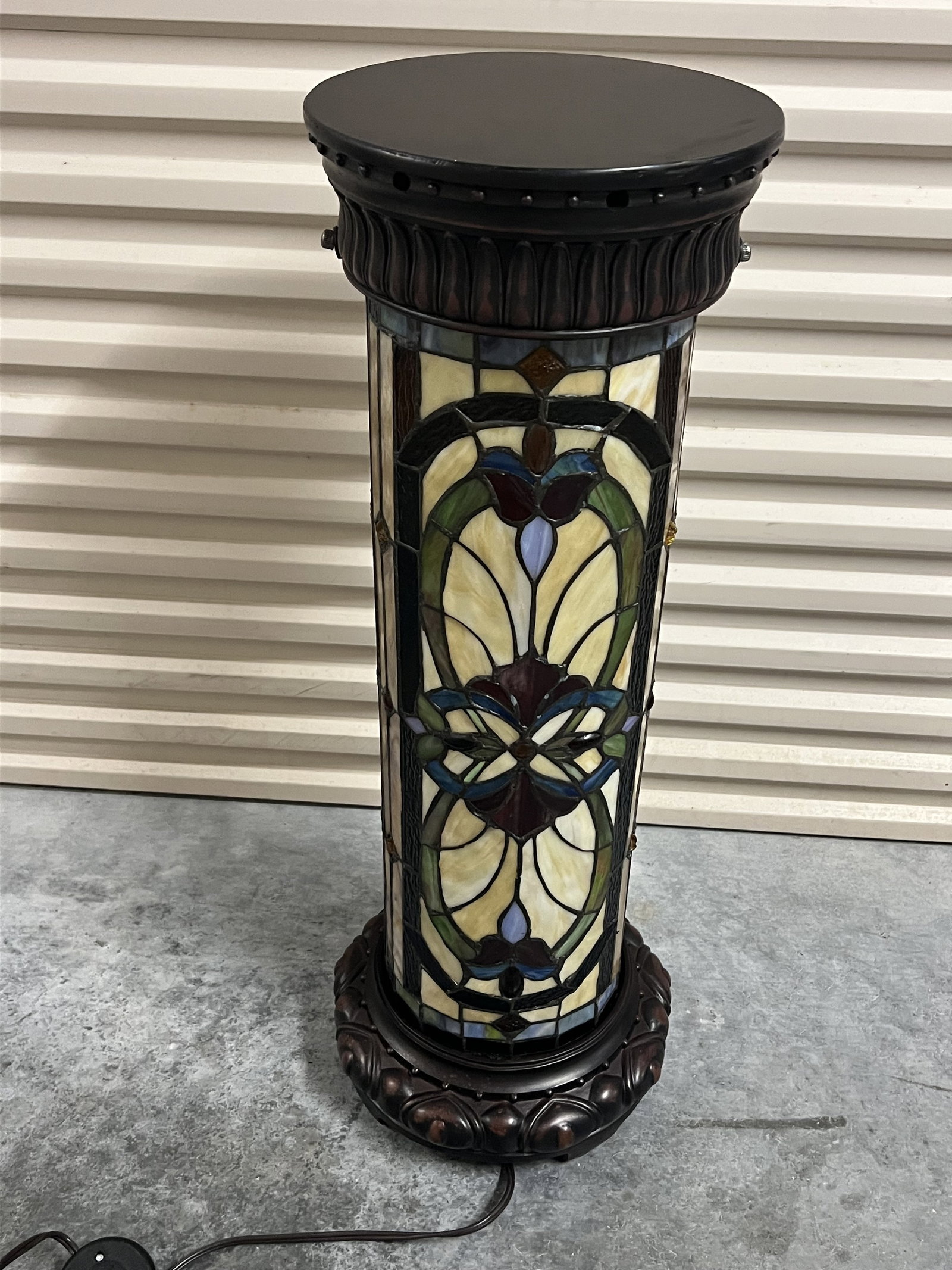 Tiffany Style Stained Glass Lighted Pedestal: Leaded glass and carved wood. Contemporary. Dimensions: 29.5" x Dia: 10" Condition: Only lightly used. Working. Low Estimate: 10.00 High Estimate: 10000.00