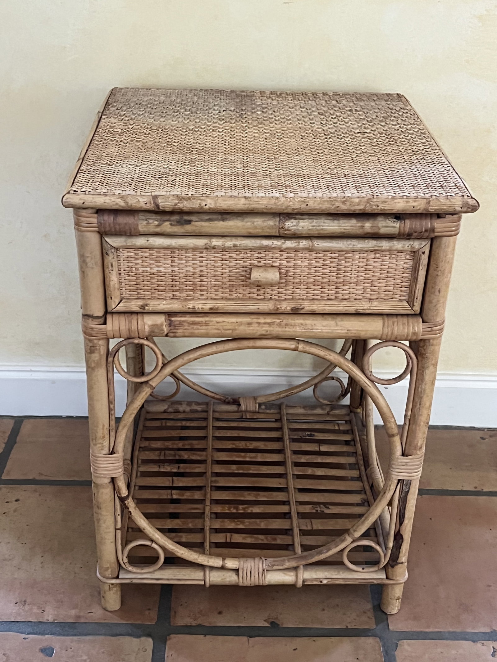 Bamboo Rattan Nightstand: Light tone bamboo, circle pattern, rattan top, single drawer. Dimensions: L 18" square: H 25" Condition: Water staining to top, sturdy. Low Estimate: 10.00 High Estimate: 10000.00