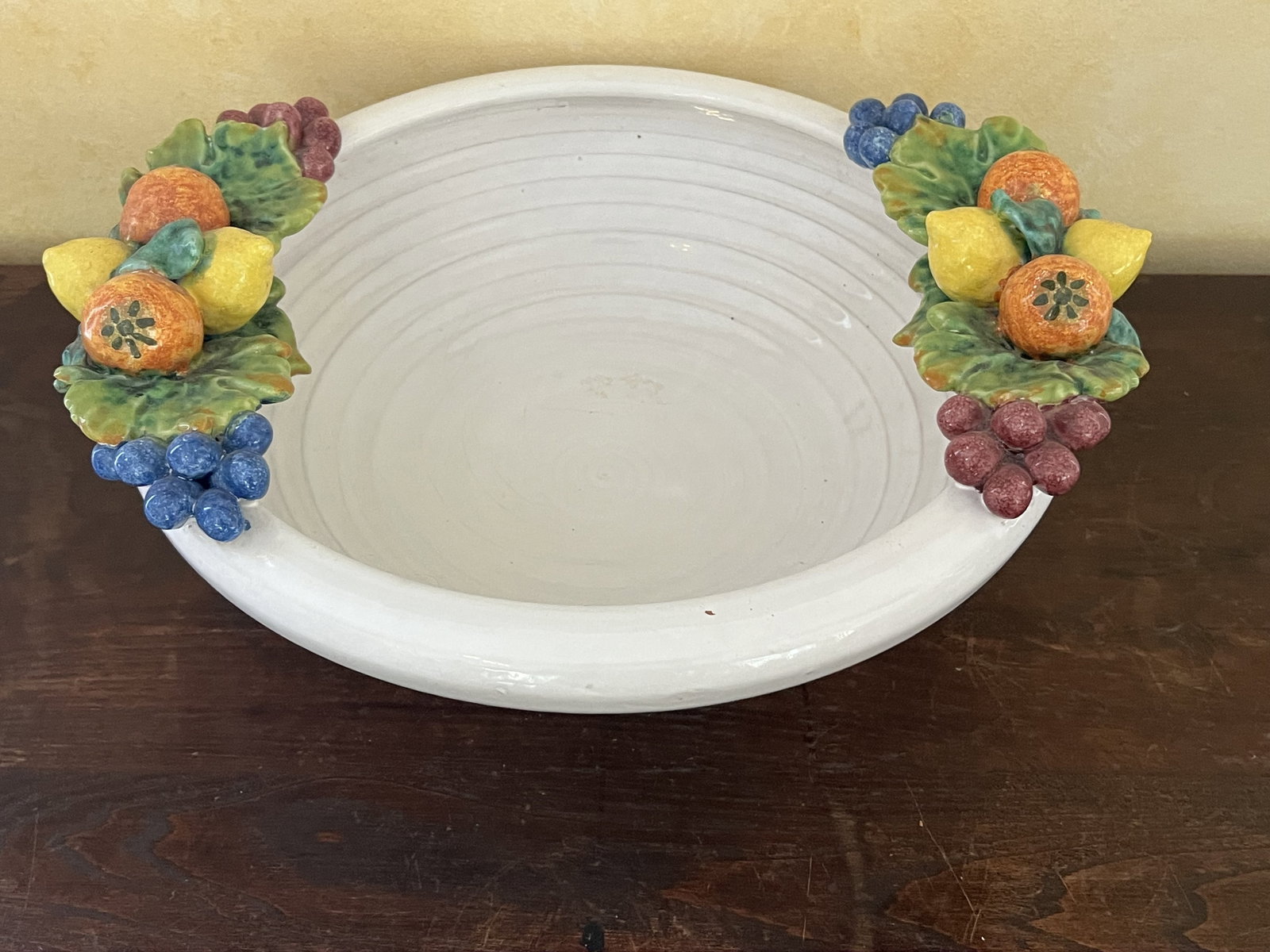 Italian Style Fruit Centerpiece Bowl: Glazed terracotta bowl with fruit handles. Dimensions: Dia: 15.5" x H 5" Condition: Minor scratches to interior surface. Low Estimate: 10.00 High Estimate: 10000.00