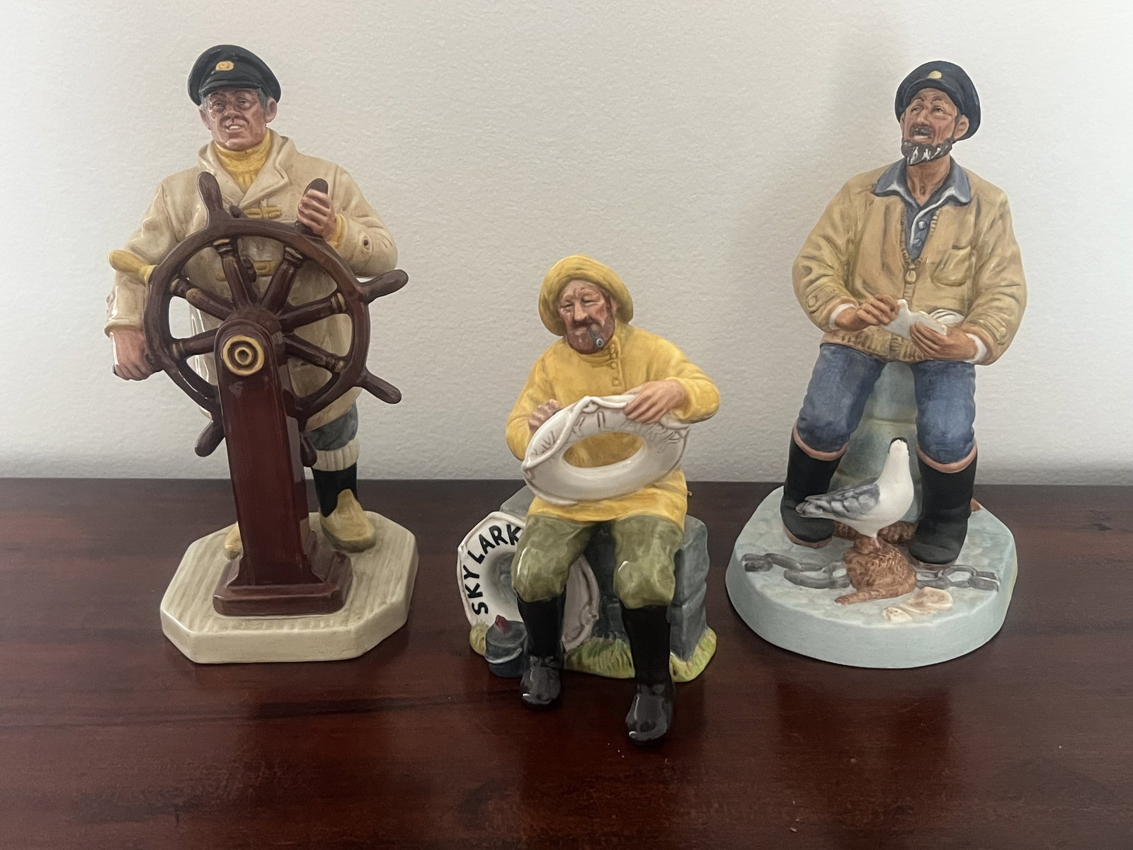 (3) Royal Doulton Sea Captain Figurines: The Helmsman HN 2499, The Boatman HN 2417, The Seafarer HN 2455. Dimensions: Largest: H 9" x W 6" Condition: Presenting well. Low Estimate: 10.00 High Estimate: 10000.00