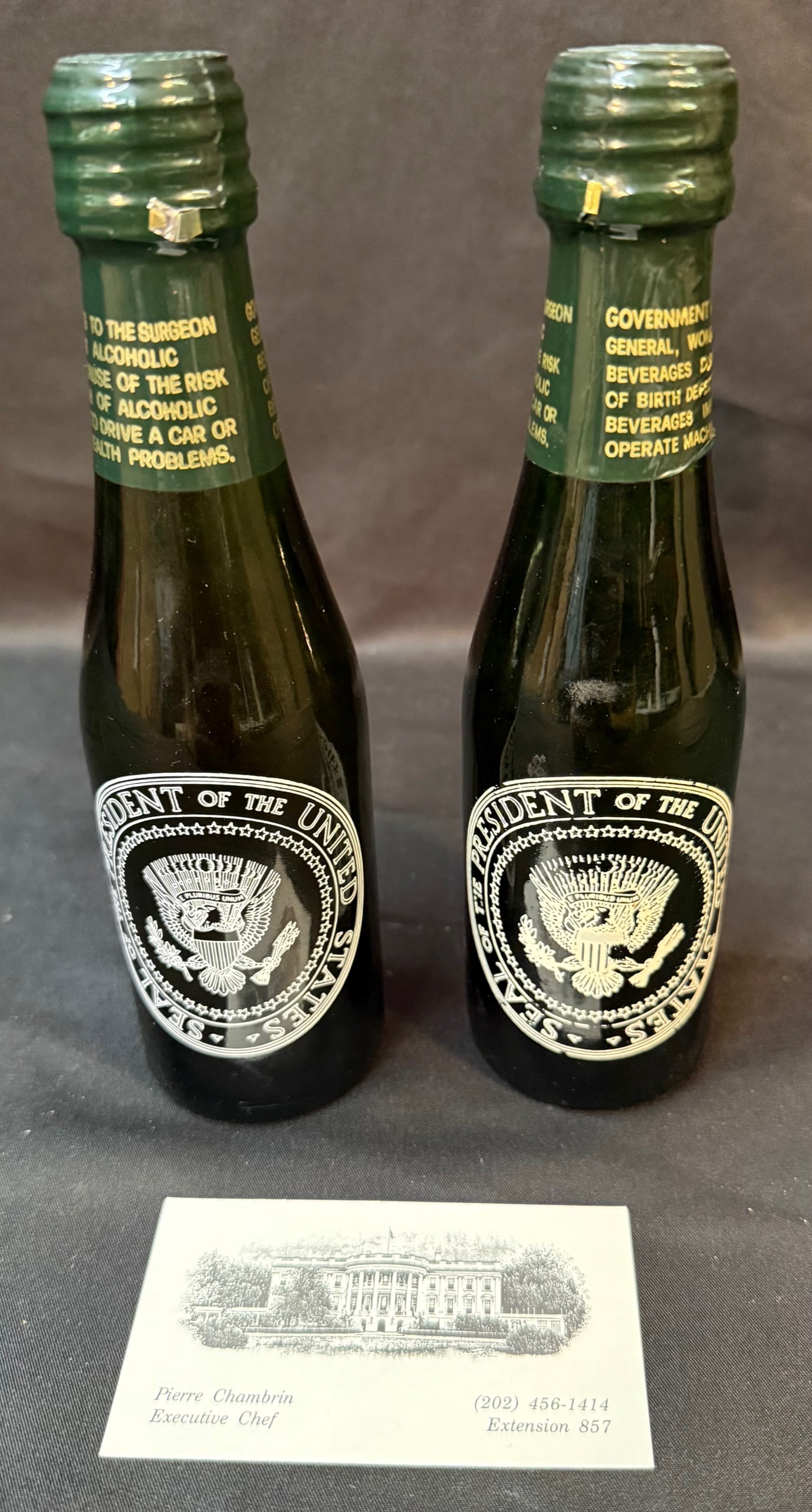 PAIR OF VINTAGE “PRESIDENTIAL SEAL?? CHAMPAGNE MINI BOTTLES, WHITE HOUSE CHEF PIERRE CHAMBRIN: A rare and visually striking pair of vintage presidential-themed miniature champagne bottles, bearing the Seal of the President of the United States and sourced directly from the estate of White House