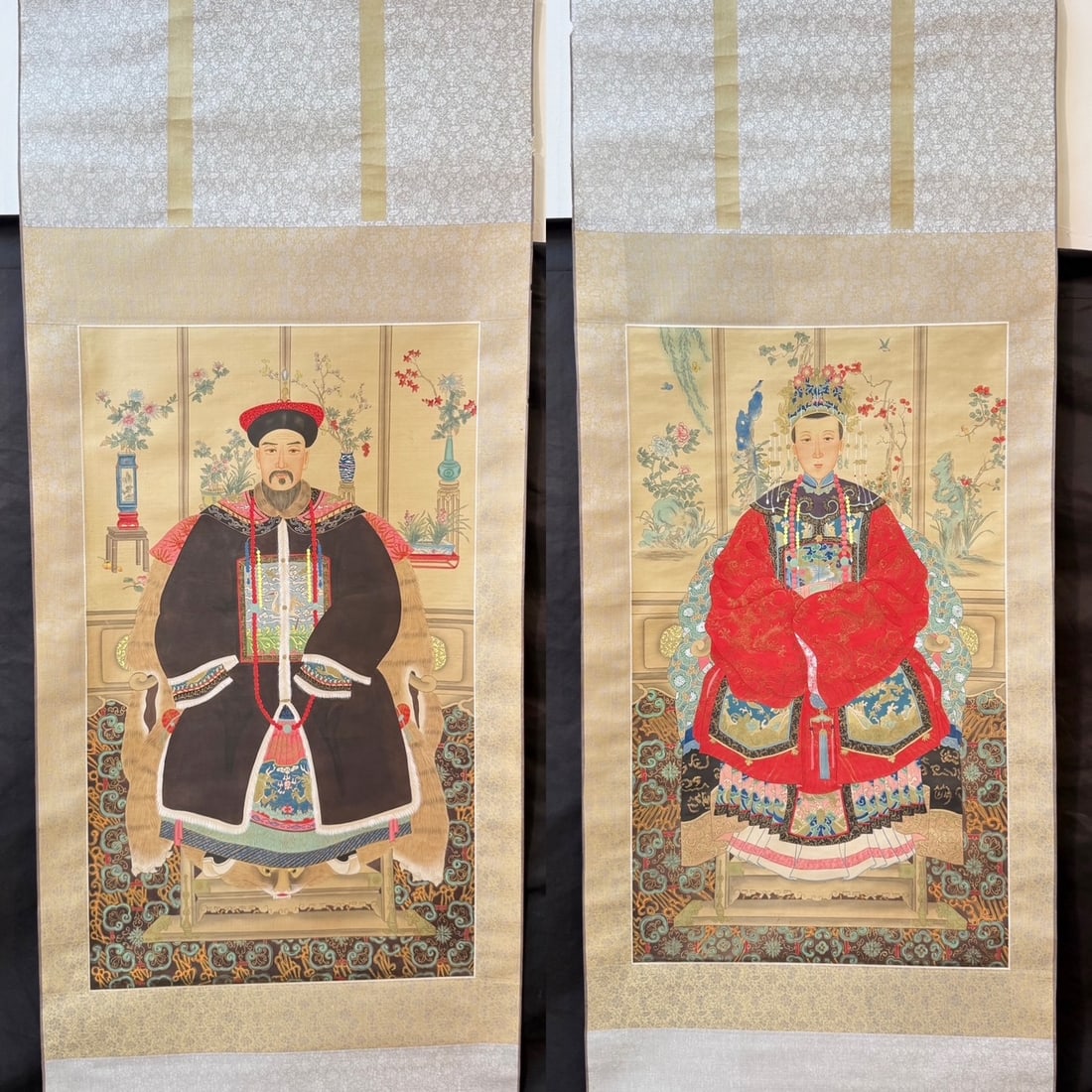 PAIR OF CHINESE QING STYLE ANCESTOR PORTRAIT HANGING SCROLLS, 1960s, 25IN x 64IN (64cm x 163cm) EACH: A decorative matching pair of Chinese ancestor portrait hanging scrolls, depicting a seated Qing dynasty court official and his consort in formal court attire. The male figure is shown wearing a 