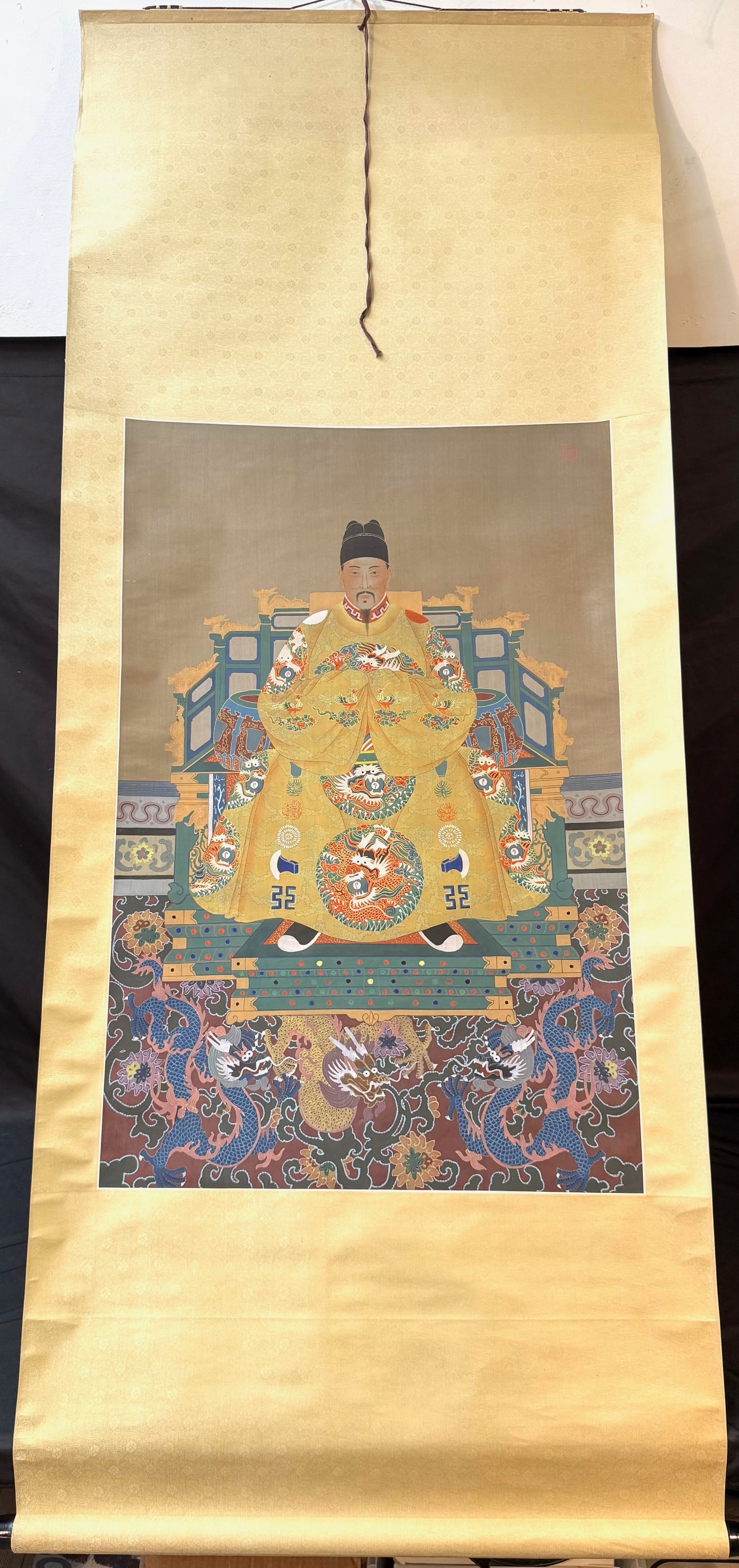 CHINESE HANGING SCROLL POTRAIT OF EMPEROR SHIZONG, 20TH CENTURY, 31IN x 74IN (79cm x 188cm): A finely executed reproduction of an official Ming dynasty imperial court portrait representing?Emperor Jiajing?(temple name Ming Shizong, r. 1521?1567). The emperor is depicted seated frontally upon 