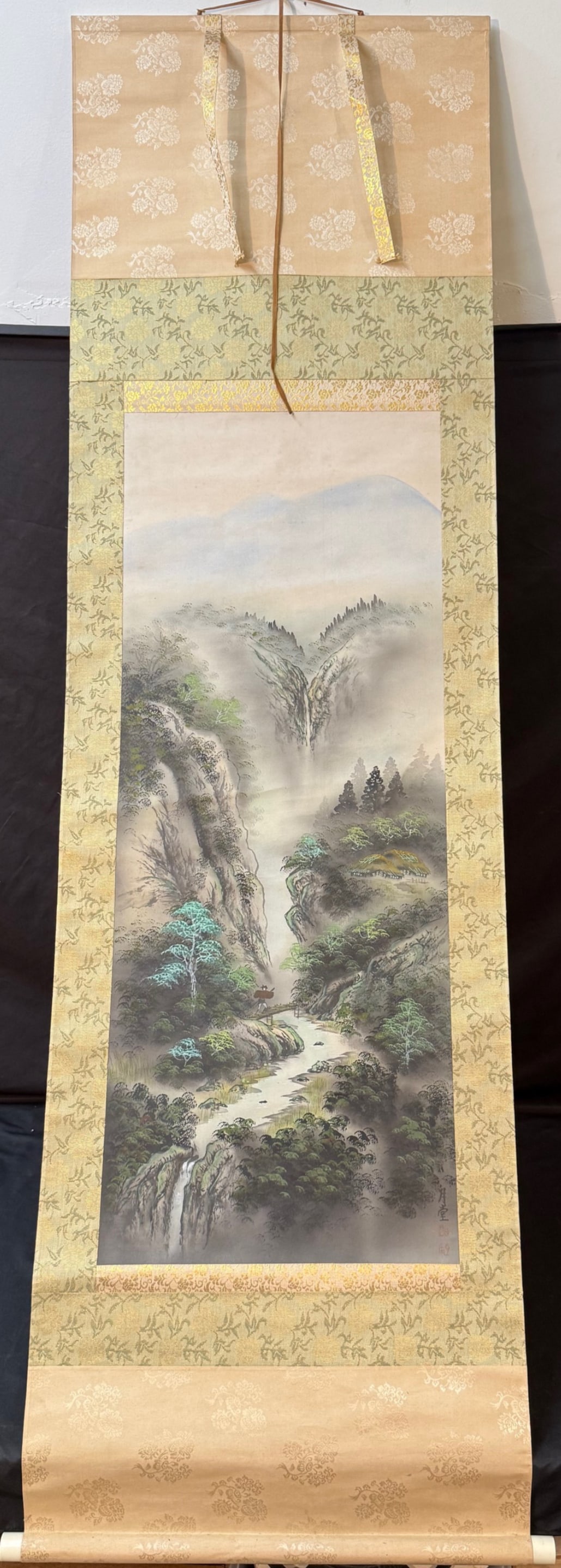 JAPANESE HANGING SCROLL PAINTING BY GETTO, 23IN x 74IN (58cm x 188cm): A finely executed Japanese hanging scroll depicting a?dramatic mountainous river landscape, rendered in layered ink washes and subtle mineral pigments. Steep rocky cliffs rise through drifting mist, o