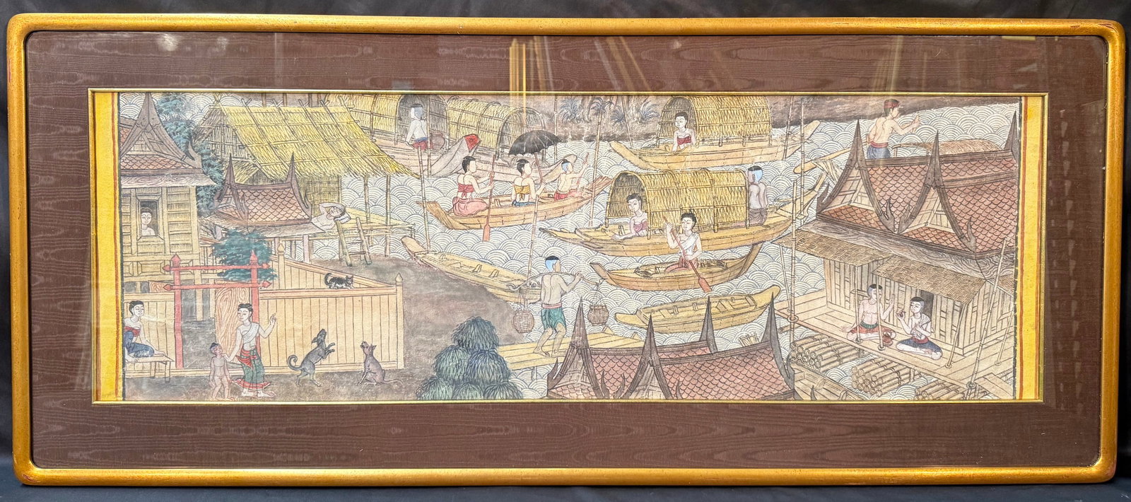 LARGE PANORAMIC THAI FLOATING VILLAGE PAINTING, 21IN x 50IN (53cm x 127cm): A captivating large-format Thai painting depicting a bustling riverside village rendered in the traditional decorative style of Southeast Asian narrative art. The composition presents an intricate pan