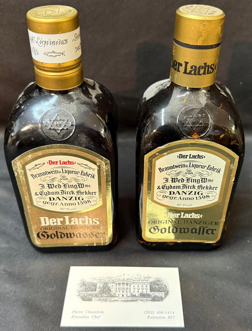 PAIR OF VINTAGE DANZIGER GOLDWASSER LIQUEURS WITH GOLD FLAKES, ?DER LACHS?, ESTATE OF WHITE HOUSE: A striking and highly display-worthy matched pair of vintage “Der Lachs” Danziger Goldwasser liqueur bottles, each filled with shimmering suspended 22kt gold flakes, and sourced from the e