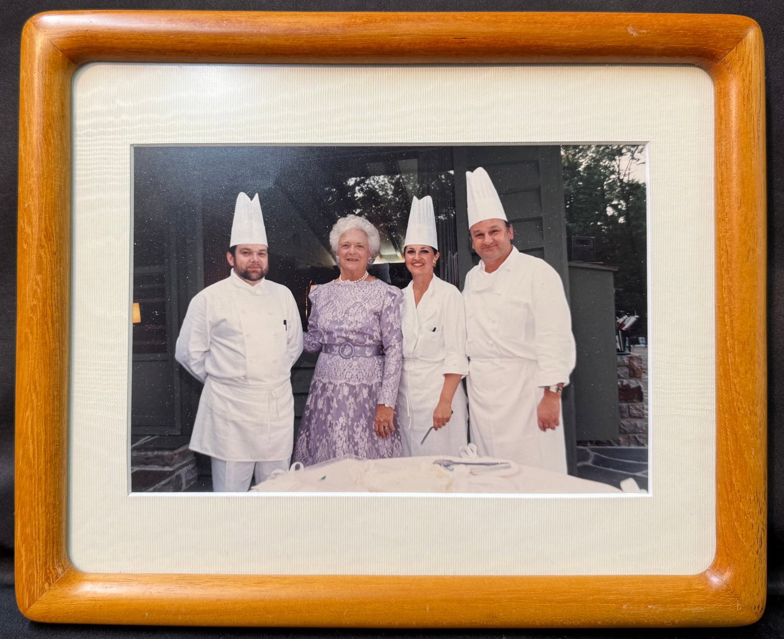 ORIGINAL FRAMED PHOTOGRAPH OF BARBARA BUSH WITH WHITE HOUSE EXECUTIVE CHEFS PIERRE CHAMBRIN & ROLAND: An exceptionally personal and historically significant photograph from the estate of Pierre Chambrin, former White House Executive Chef, depicting Former First Lady Barbara Bush together with three me