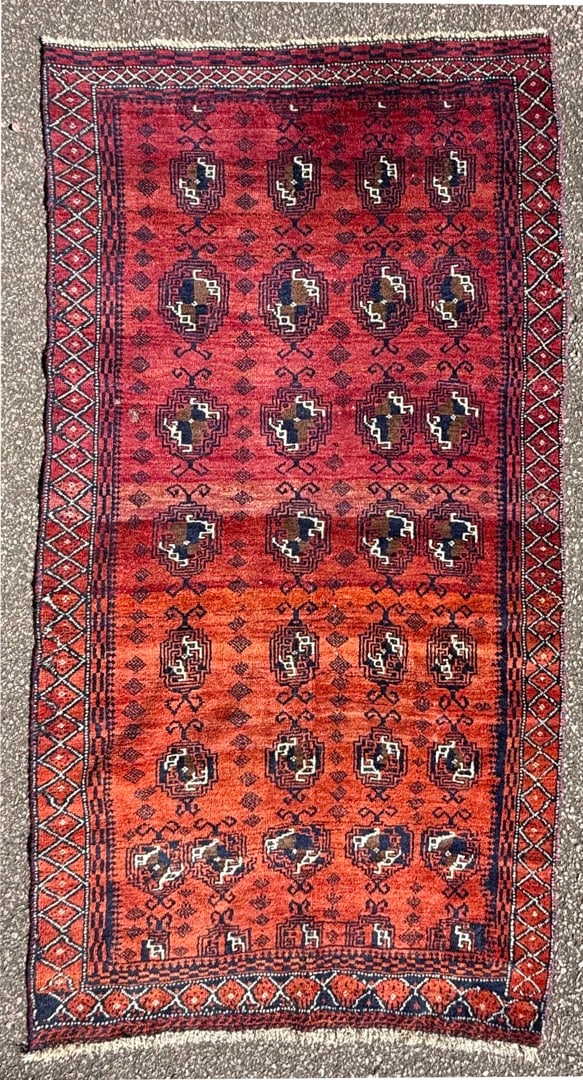 VINTAGE HAND-KNOTTED PAKISTANI BUKHARA RUG, 3.5 x 6.5 (104cm x 196cm): A striking, vintage hand-knotted Pakistani Bukhara tribal rug featuring a dramatic crimson field and framed by intricate tribal borders. Handwoven in wool, this rug’s strong geometric compositio