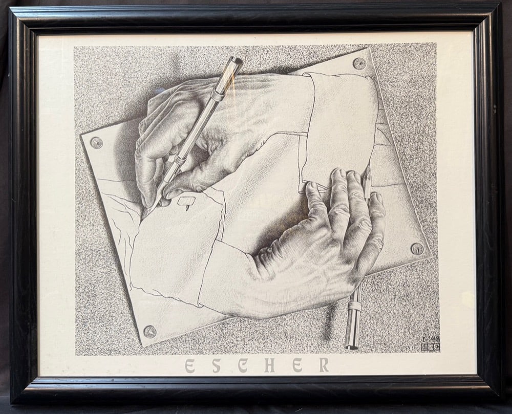 M.C. ESCHER (1898-1972) 1948 ICONIC SURREALIST GRAPHIC ART TITLED DRAWING HANDS, 25.5IN x 31.5IN: Striking large-format framed print reproducing one of the most celebrated and immediately recognizable compositions by legendary Dutch graphic artist Maurits Cornelis Escher. Drawing Hands stands amon