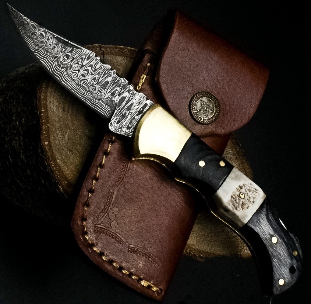 Cast Bolster Wood Scale Damascus Folder Knife: Size: Length 17.8 cm - Blade 7.6 cm. Materials: Damascus steel, wood, brass, leather. Condition: New. This folding pocket knife features a blade forged from Damascus steel, displaying the distinctive