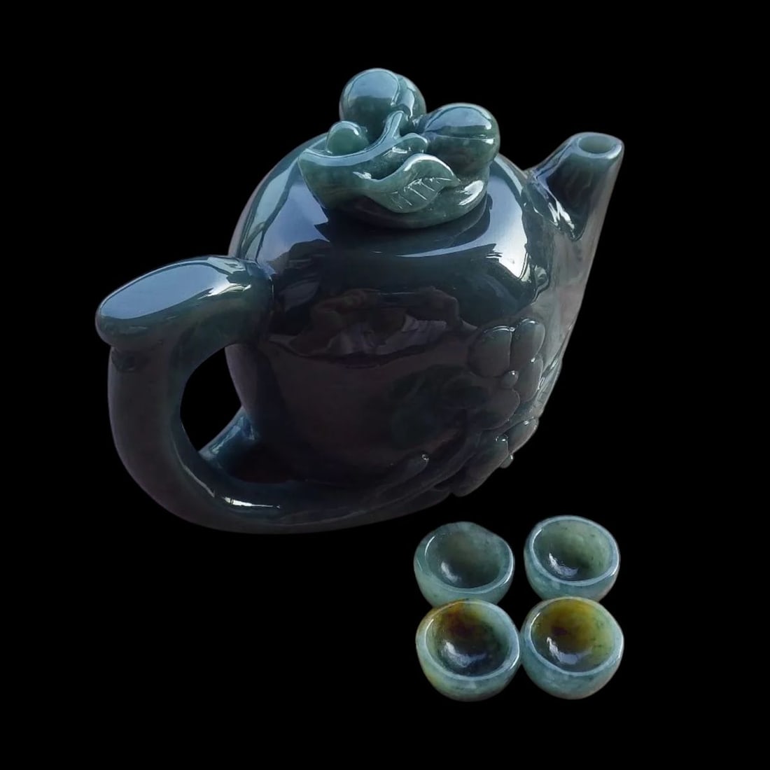 Dark Green Jade Carved Relief Design Tea Tableware: Size: Height 4.9 cm - Length 7.5 cm - Width 4.3 cm. Weight 175 g. Materials: Jade. Condition: Excellent. This dark green jade tea set is a finely crafted piece featuring a relief-carved peach and flow