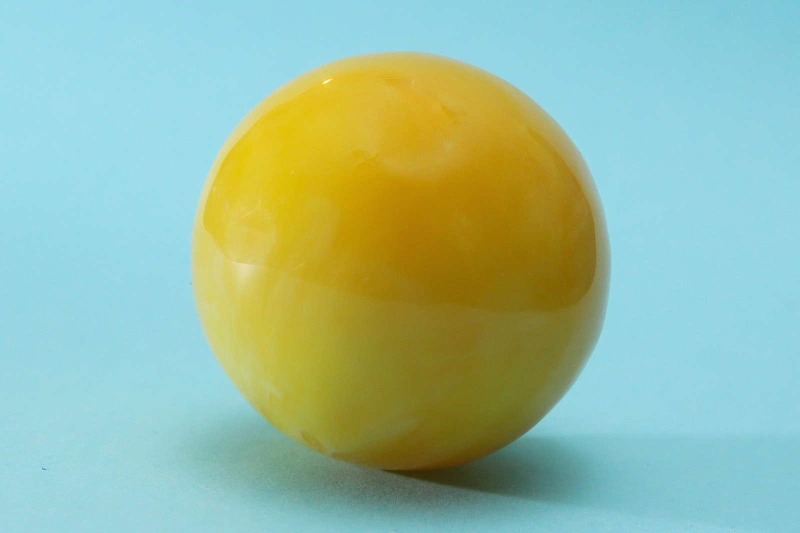 Sun-Hued Orb Figurine Baltic Amber Bakelite Style: This abstract sculpture features a striking yellow ball figurine made from Baltic amber and bakelite or composite materials. Its bold color and modern design make it a unique and eye-catching piece, p