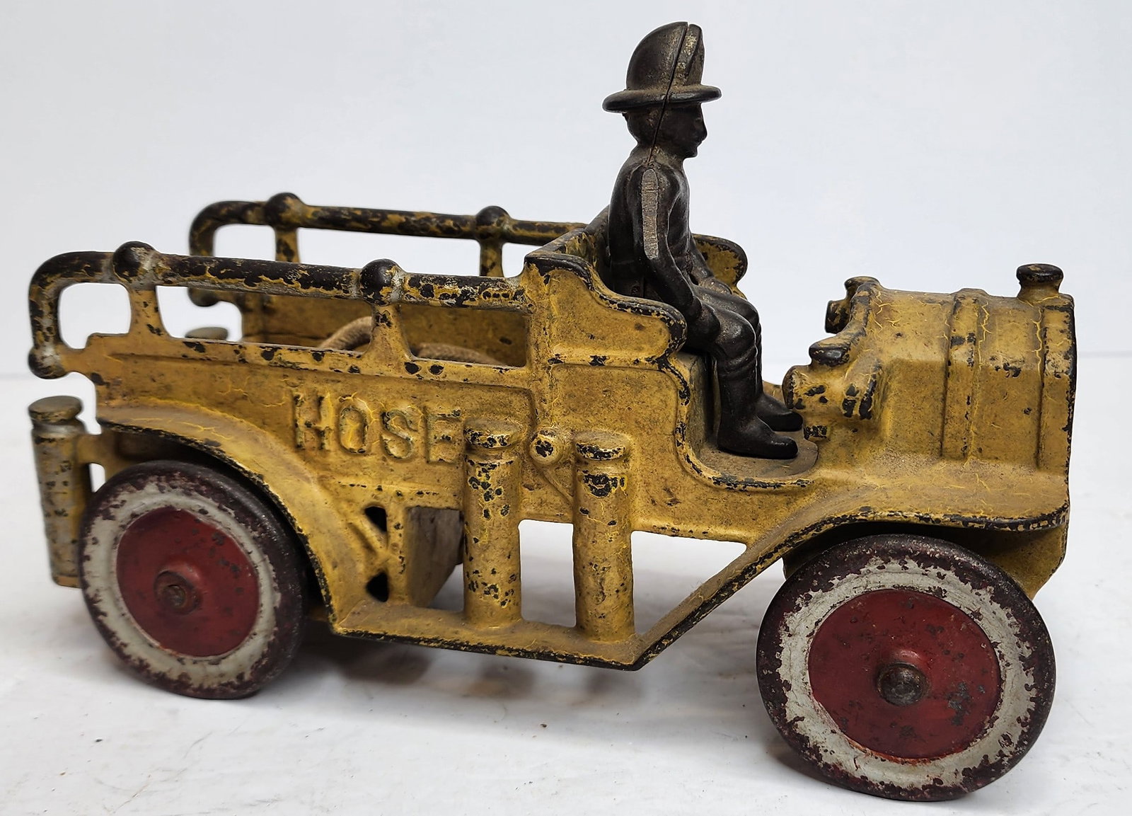 Cast Iron Motorized Hose Wagon Toy: Cast iron yellow hose wagon toy complete with driver. Measures 8 1/2" in length