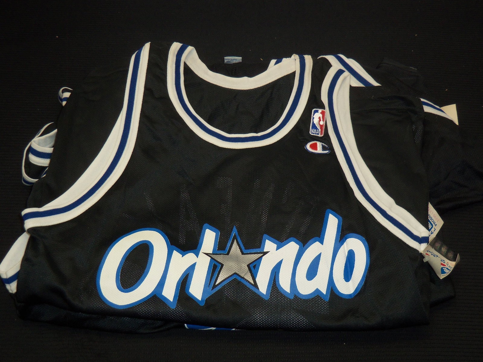 SHAQUILLE O'NEAL REPLICA BLACK JERSEYS BY CHAMPION - 7 JERSEYS: Lot of 7 Shaquille O'Neal Orlando Magic replica black jerseys by Champion. The sizes included are: 36 (2); 40 (1); 44 (2) and 48 (2).