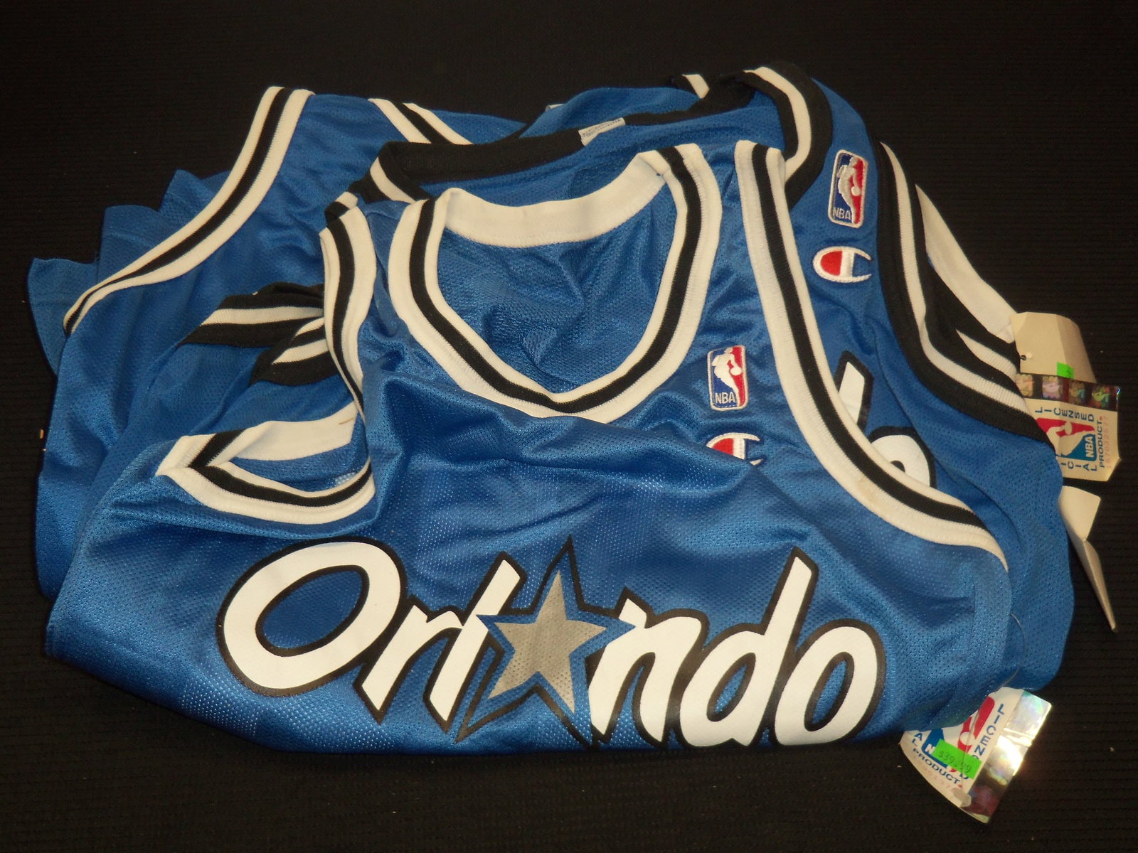 SHAQUILLE O'NEAL REPLICA BLUE JERSEYS BY CHAMPION - 5 JERSEYS: Lot of 5 Shaquille O'Neal Orlando Magic replica blue jerseys by Champion. The sizes included are: 36 (1); 40 (2) and 44 (2).