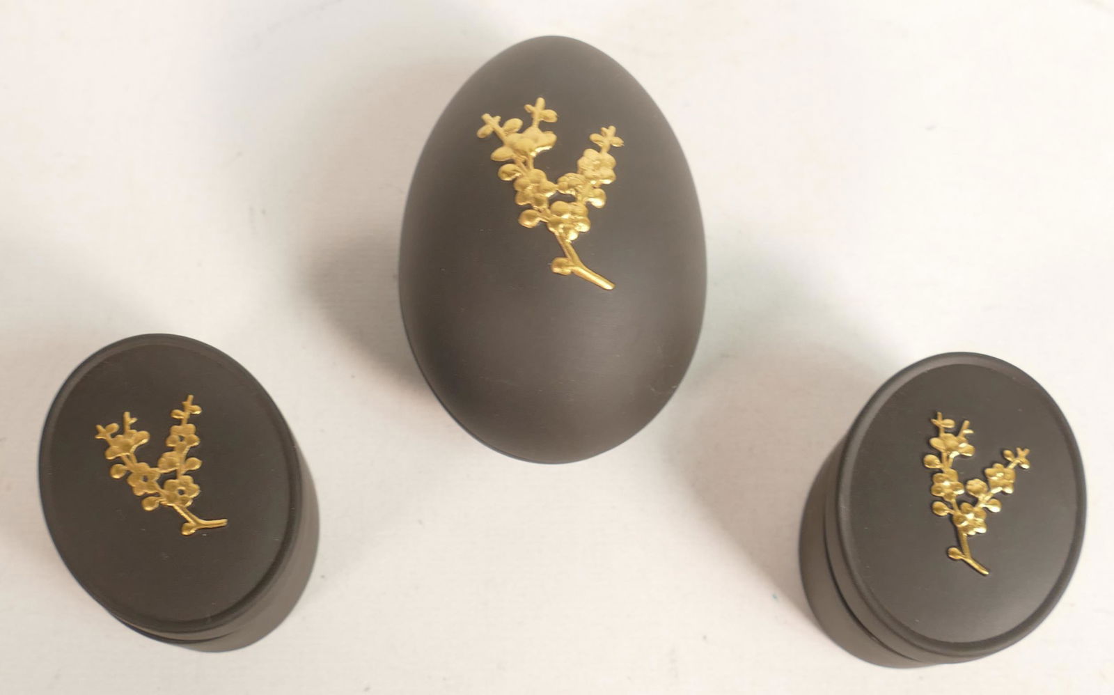 A group of 3 Wedgwood gilded black Basalt boxes. Decorated in Prunus Blossom. One in egg form, two (1 of 2)
