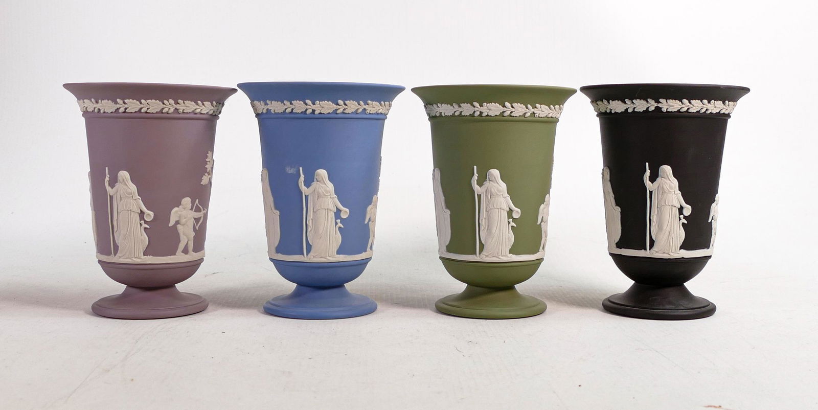A collection of Wedgwood Jasper ware vases, in various colours to include lilac, black, Sage green: A collection of Wedgwood Jasper ware vases, in various colours to include lilac, black, Sage green and pale blue. Measure 13cm in height. (4)
