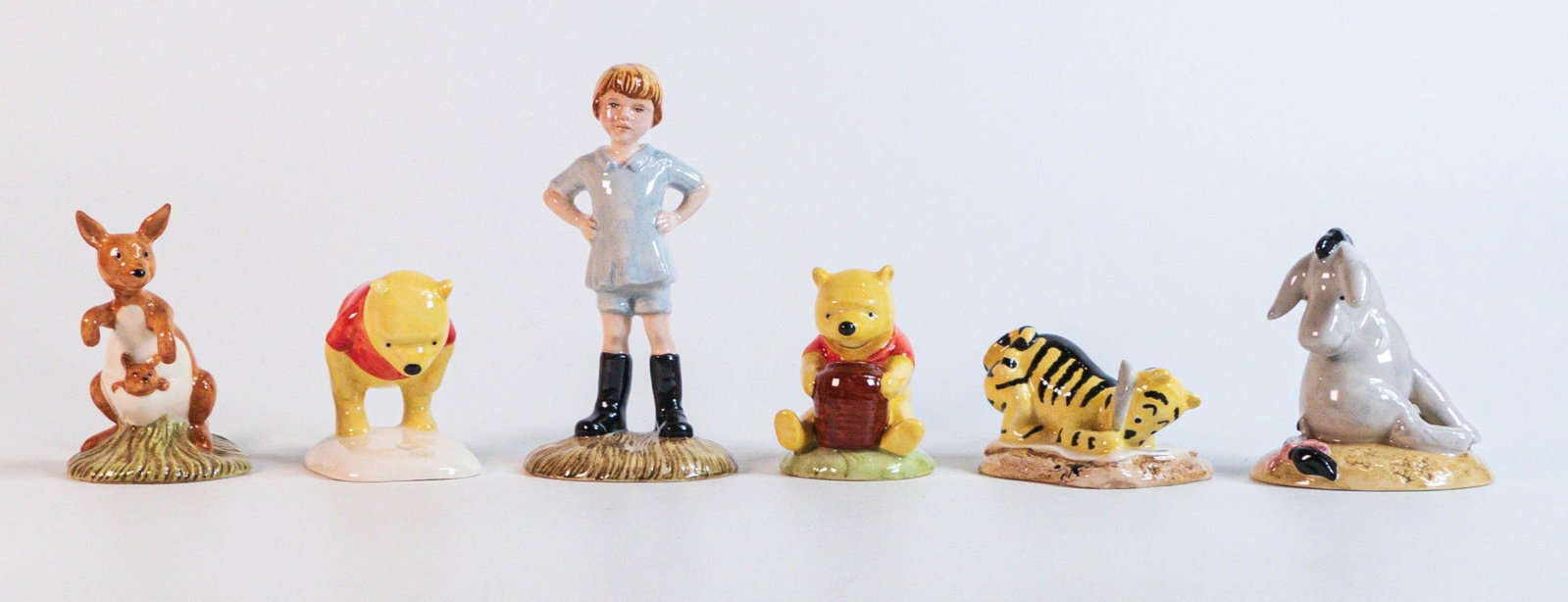 Royal Doulton Winnie the Pooh figures for the 70th Anniversary to include Christopher Robin, Eeyore,: Royal Doulton Winnie the Pooh figures for the 70th Anniversary to include Christopher Robin, Eeyore, Kanga, Winnie the Pooh, Tigger and Winnie The Pooh with Honey Pot. (6)