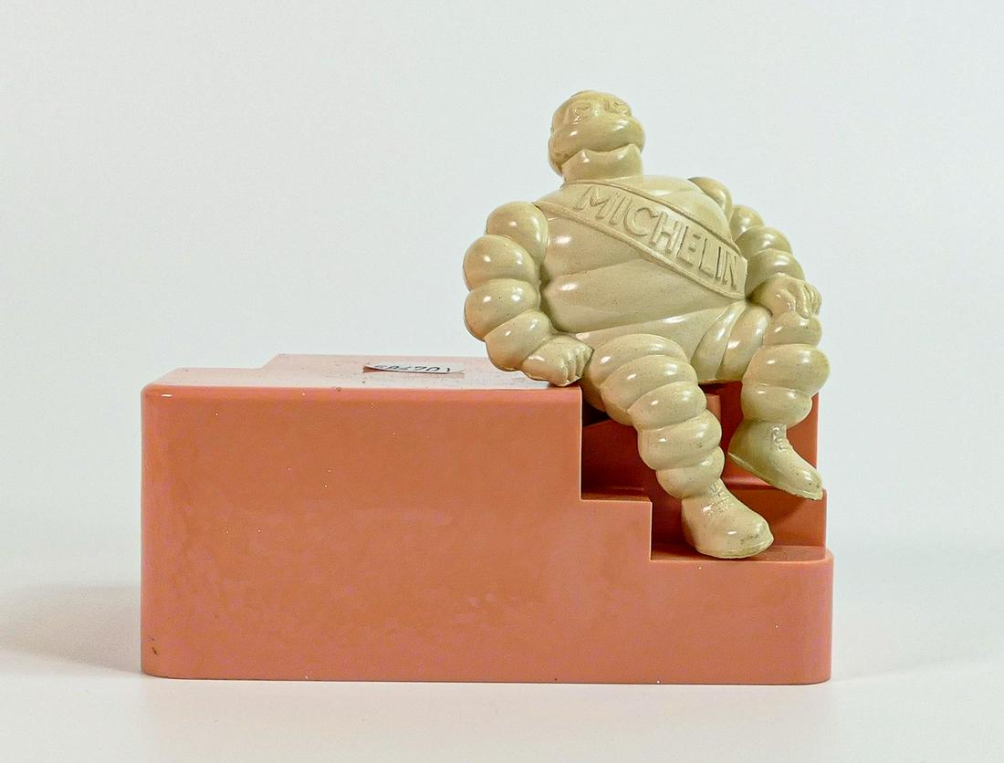 Michelin bakelite employees money box, modelled as a seated Mr Bibendum to pink base, h.13cm x: Michelin bakelite employees money box, modelled as a seated Mr Bibendum to pink base, h.13cm x w.15cm