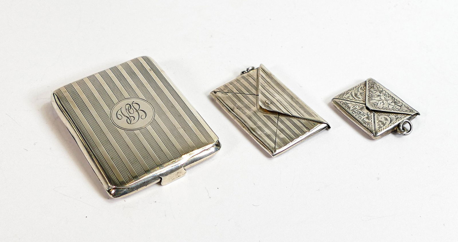 Silver stamp case Chester 1911 maker AE Jones, together with double stamp case marked sterling and a: Silver stamp case Chester 1911 maker AE Jones, together with double stamp case marked sterling and a hallmarked silver case for a book of matches - Some denting to double stamp case. (3)