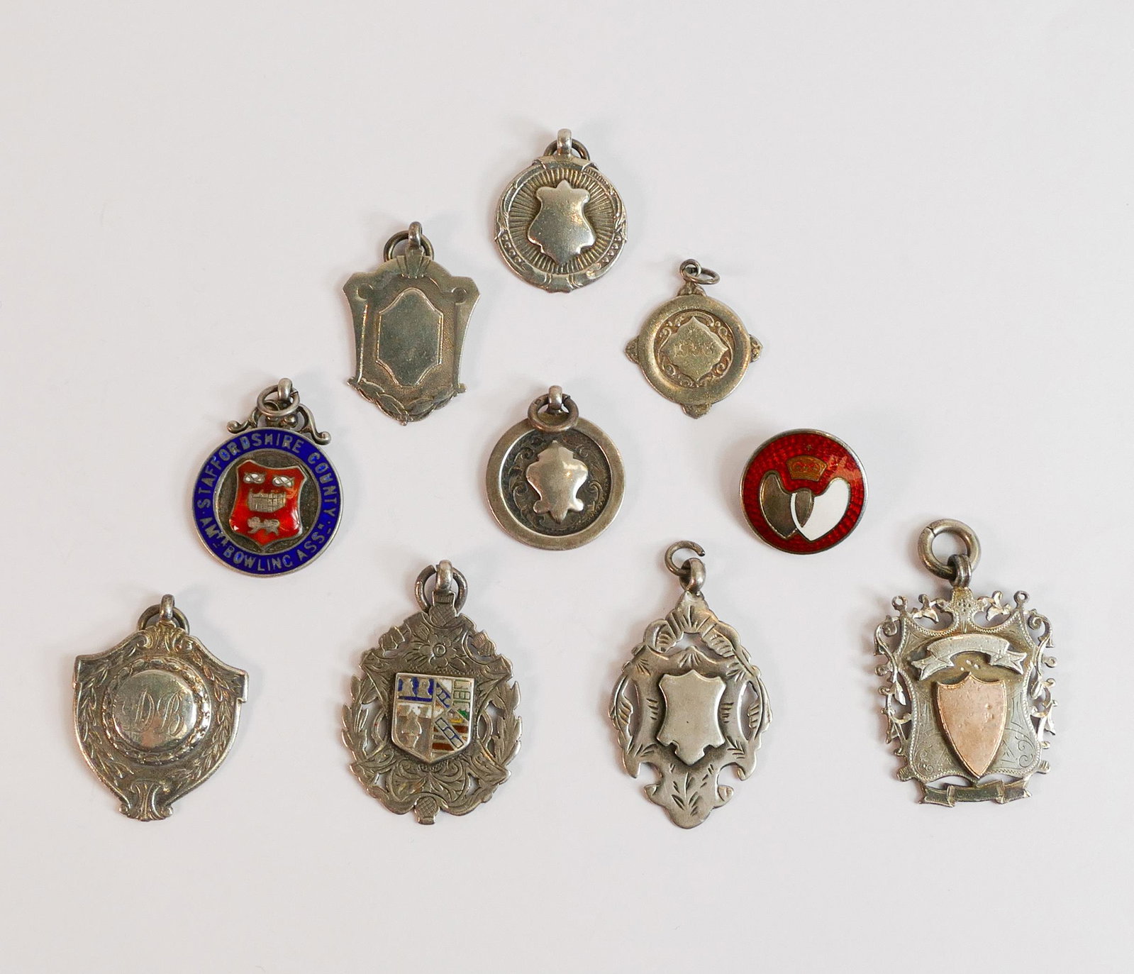 A good collection of silver shield medals including enamelled Staffordshire County Bowling badge,: A good collection of silver shield medals including enamelled Staffordshire County Bowling badge, gold on silver badge etc., 84.7g. (10)